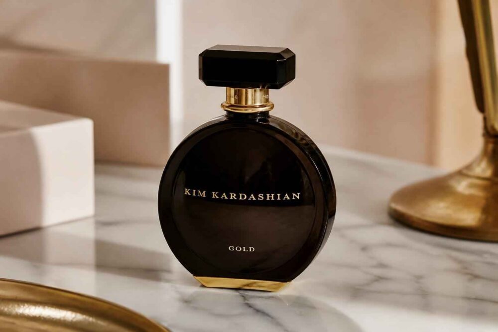Czarny flakon perfum Kim Kardashian stojący na marmurowym blacie obok złotej lampy