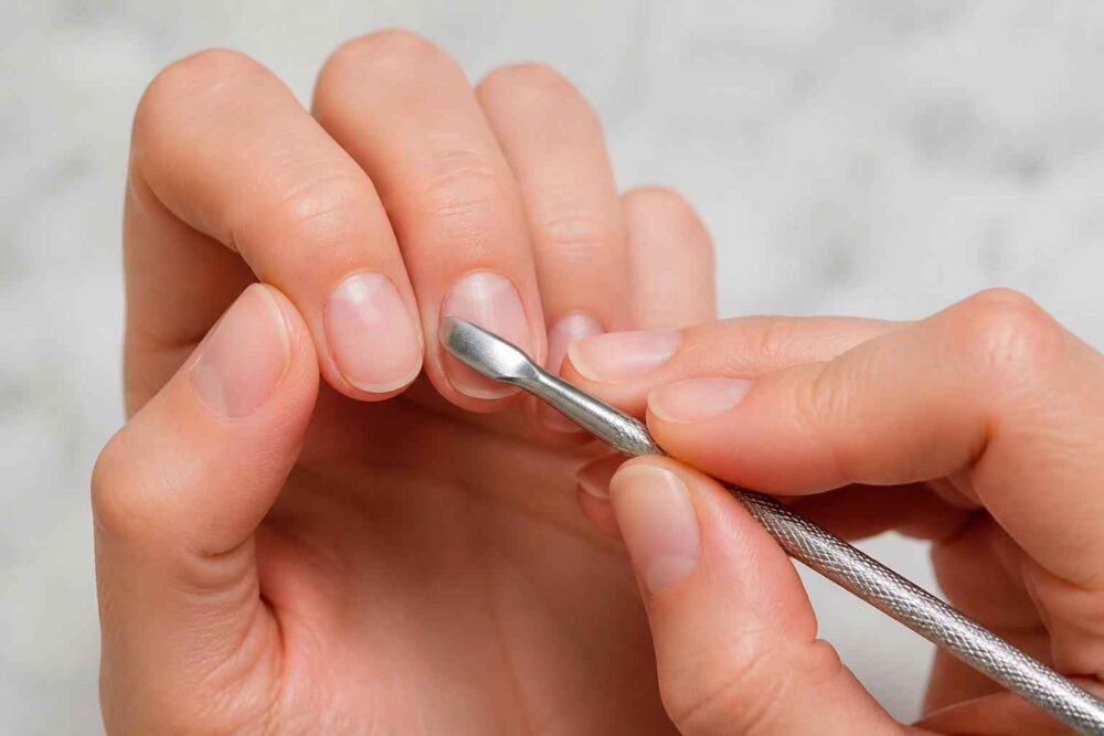 Manicure z użyciem metalowego narzędzia do odsuwania skórek przy paznokciu